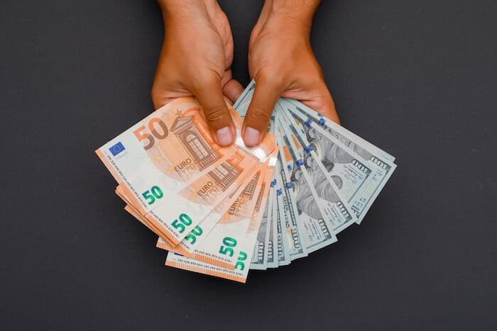 Ruce držící vějíře bankovek v eurech a amerických dolarech